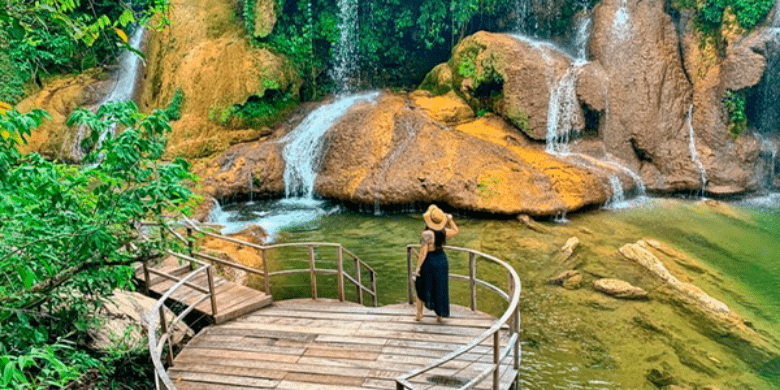 Pessoa contemplando cachoeira de águas cristalinas com paisagem de mata verde e vasta ao redor - curtindo descontos em Bonito MS