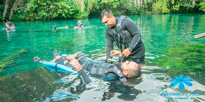 Guia turístico auxiliando pessoa com mobilidade reduzida na flutuação na Nascente Azul