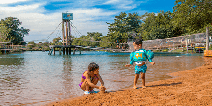 Uma menina e um menino brincando na areia da Praia de Água Doce ilustrando o que fazer em Bonito no dia das