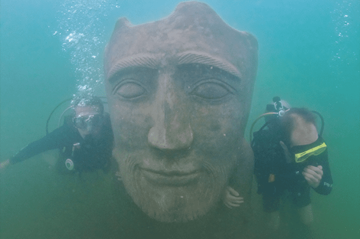 Duas pessoas mergulhando com cilindro e contemplando estátua submersa - Museu Subaquático de Bonito MS - Nascente Azul