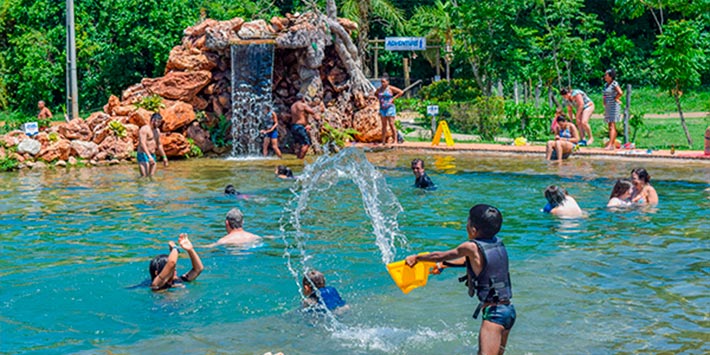 Crianças e adultos brincando na piscina natural e ecológica formada por lago de água cristalina que passa pela Nascente Azul - Páscoa em Bonito MS com toda a família