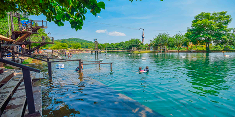 Famílias se divertindo em feriado de 7 de setembro em balneário com tirolesas aquáticas passando sobre o lago cristalino